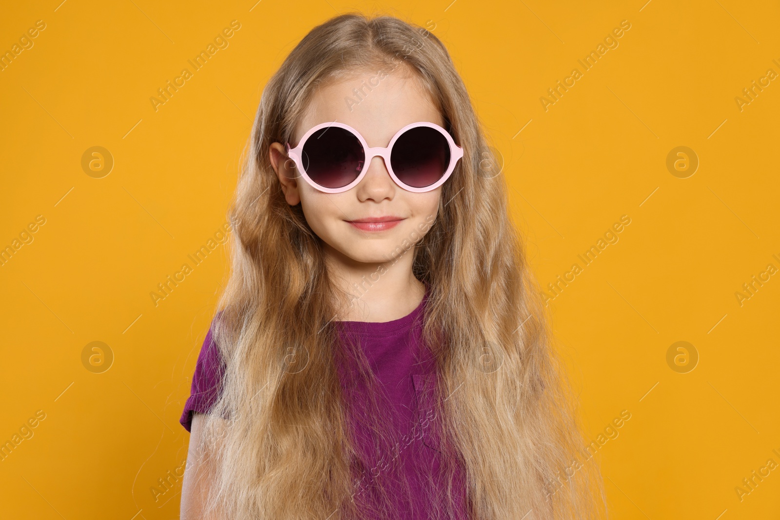 Photo of Girl in stylish sunglasses on orange background