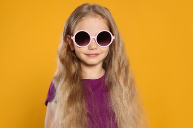 Photo of Girl in stylish sunglasses on orange background