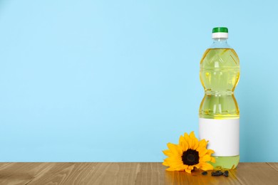Photo of Bottle of cooking oil, sunflower and seeds on wooden table, space for text