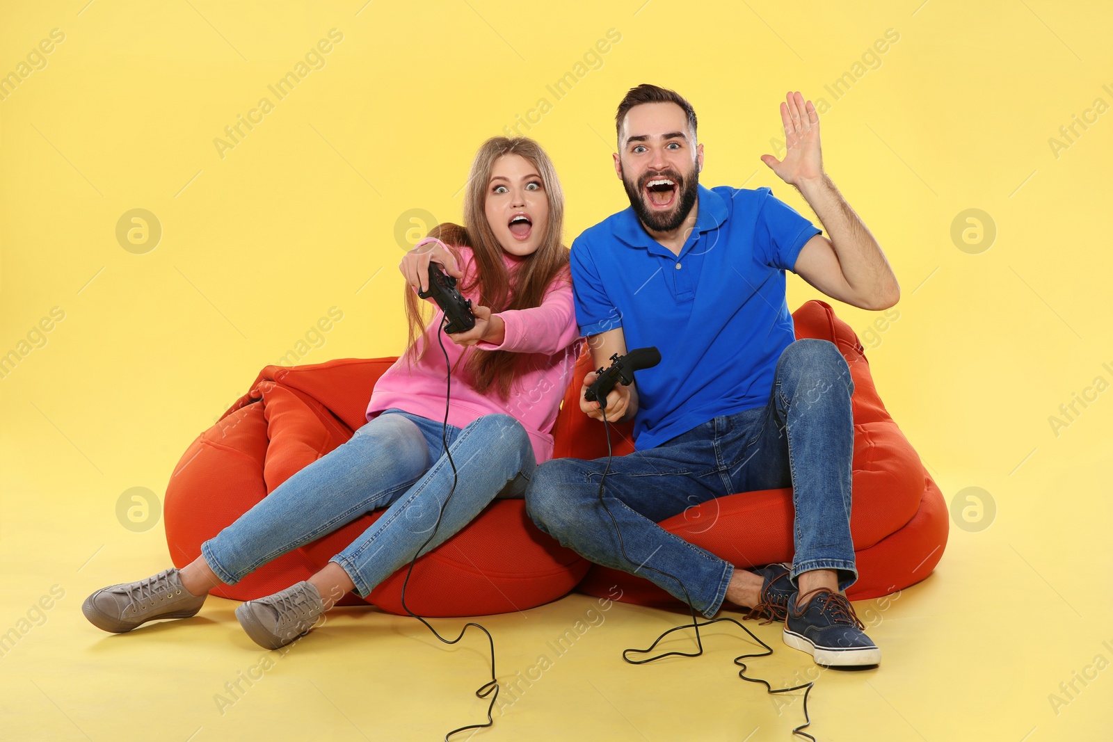 Photo of Emotional couple playing video games with controllers on color background