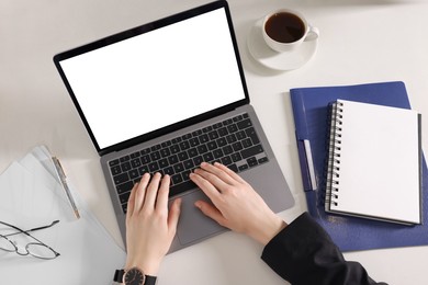 Woman working with laptop at white desk, top view