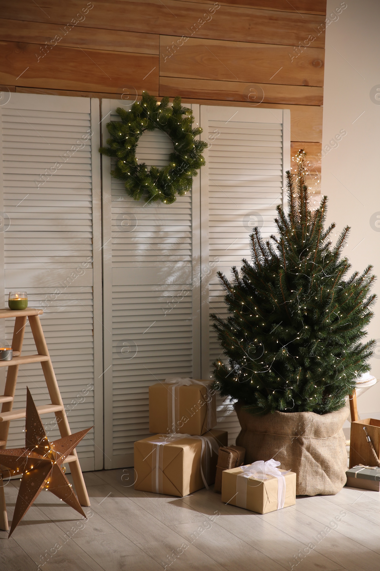 Photo of Spacious room with small Christmas tree and wreath. Interior design