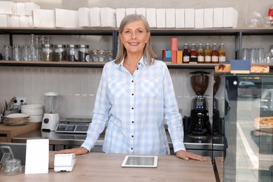 Photo of Portrait of happy business owner at cashier desk in her cafe