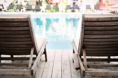 Photo of Comfortable wooden loungers at clean swimming pool