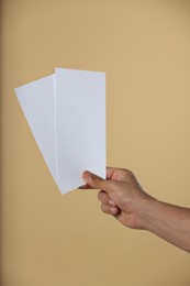 Photo of Man holding flyers on beige background, closeup. Mockup for design