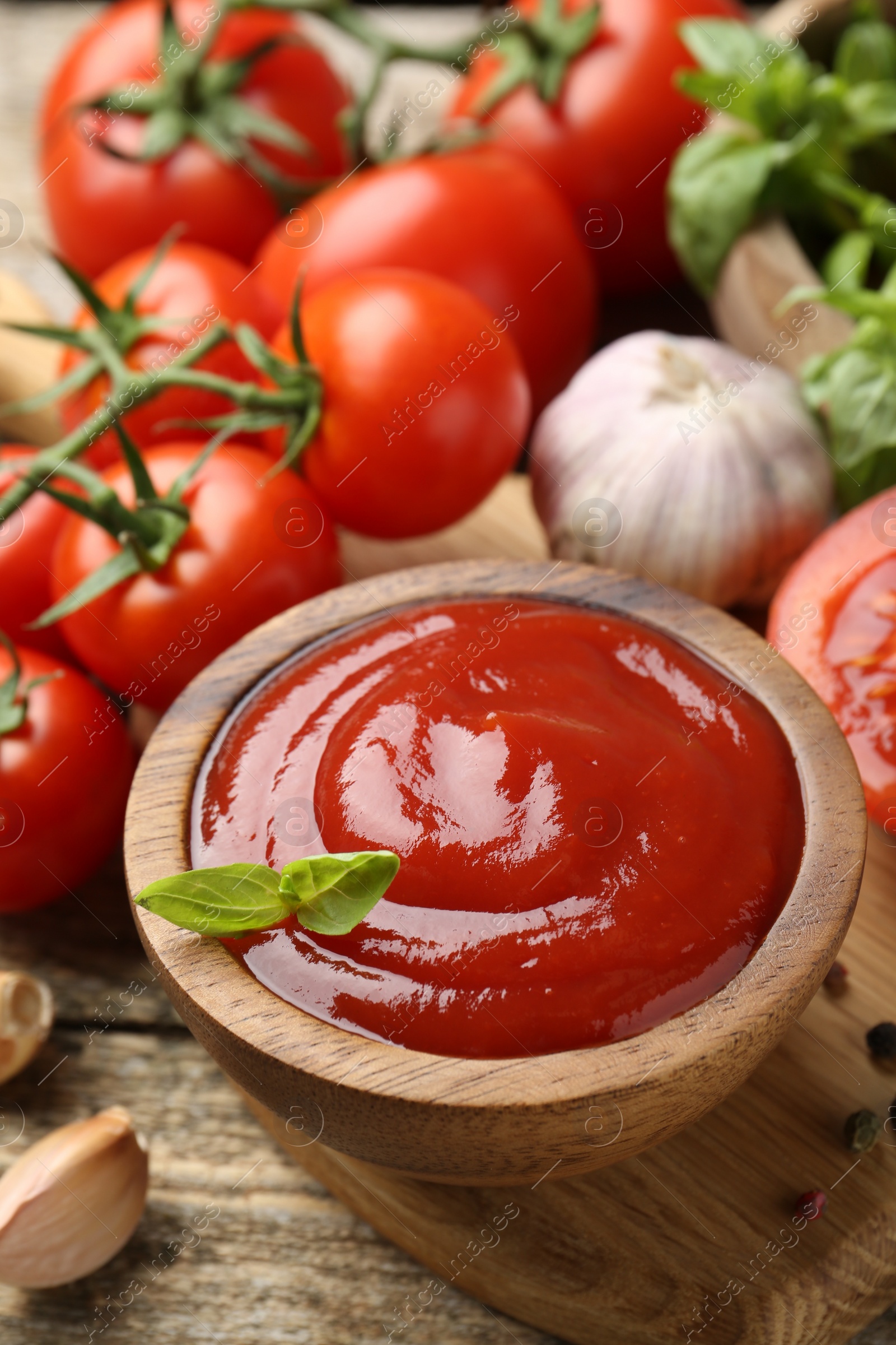 Photo of Tasty ketchup, fresh tomatoes, basil and spices on wooden table