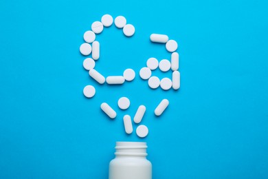 Photo of Open bottle and calcium symbol made of white pills on light blue background, flat lay