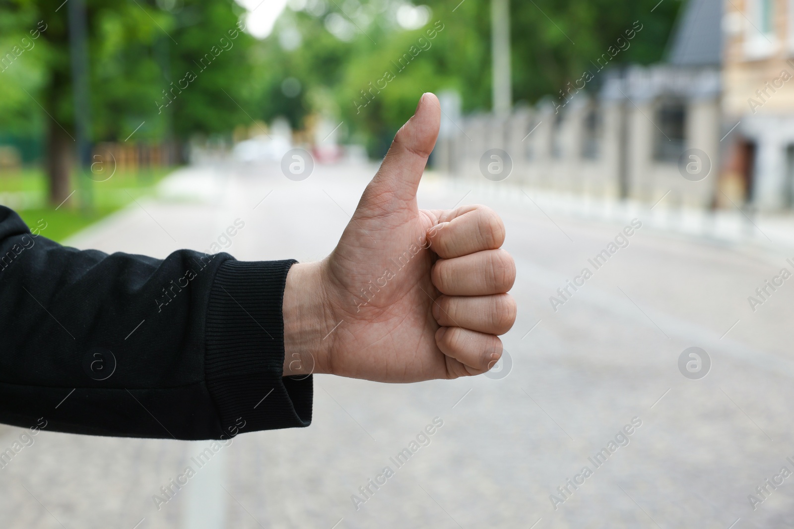 Photo of Man catching car on city street, closeup. Hitchhiking trip