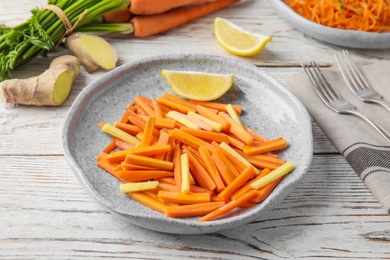 Photo of Plate with tasty carrot salad on wooden table