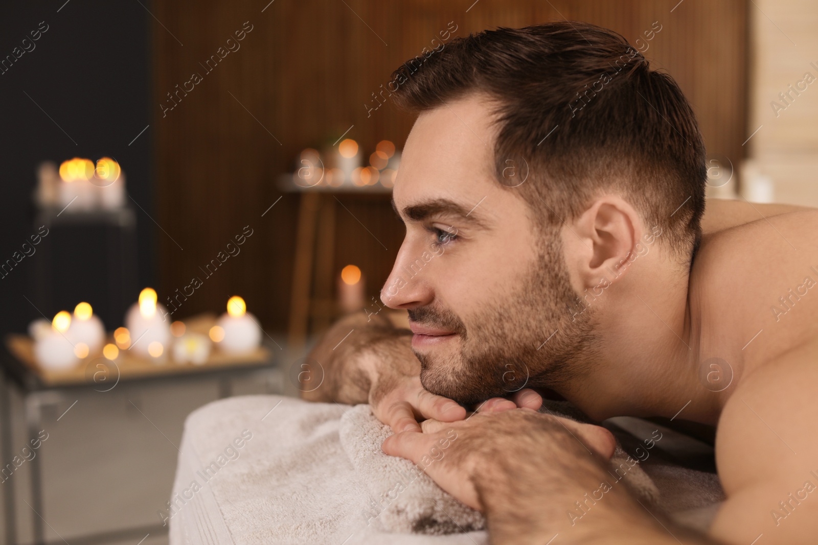 Photo of Handsome man relaxing on massage table in spa salon. Space for text