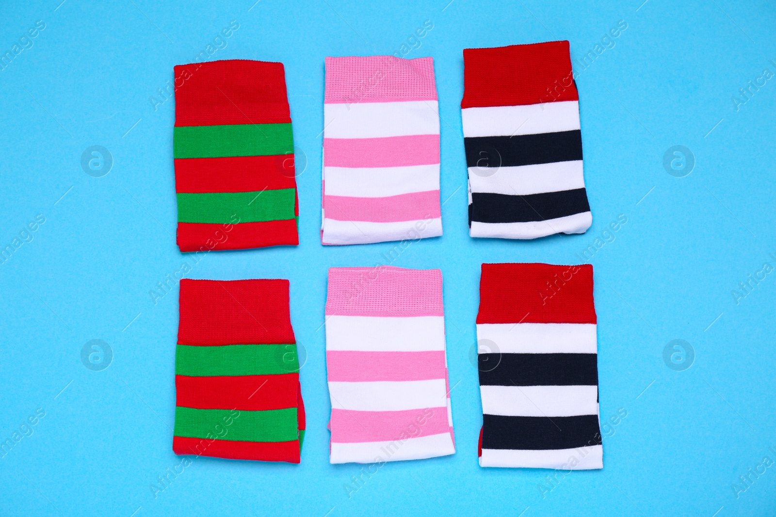 Photo of Different striped socks on light blue background, flat lay