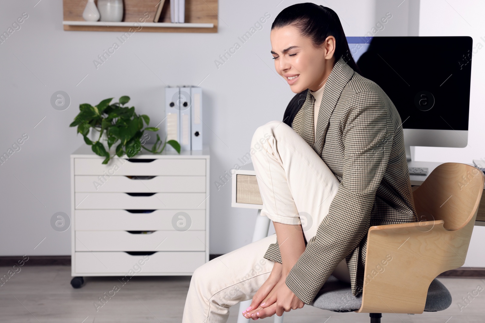 Photo of Young woman rubbing sore foot in office. Space for text