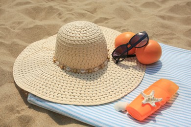 Photo of Beach accessories and oranges on sand outdoors