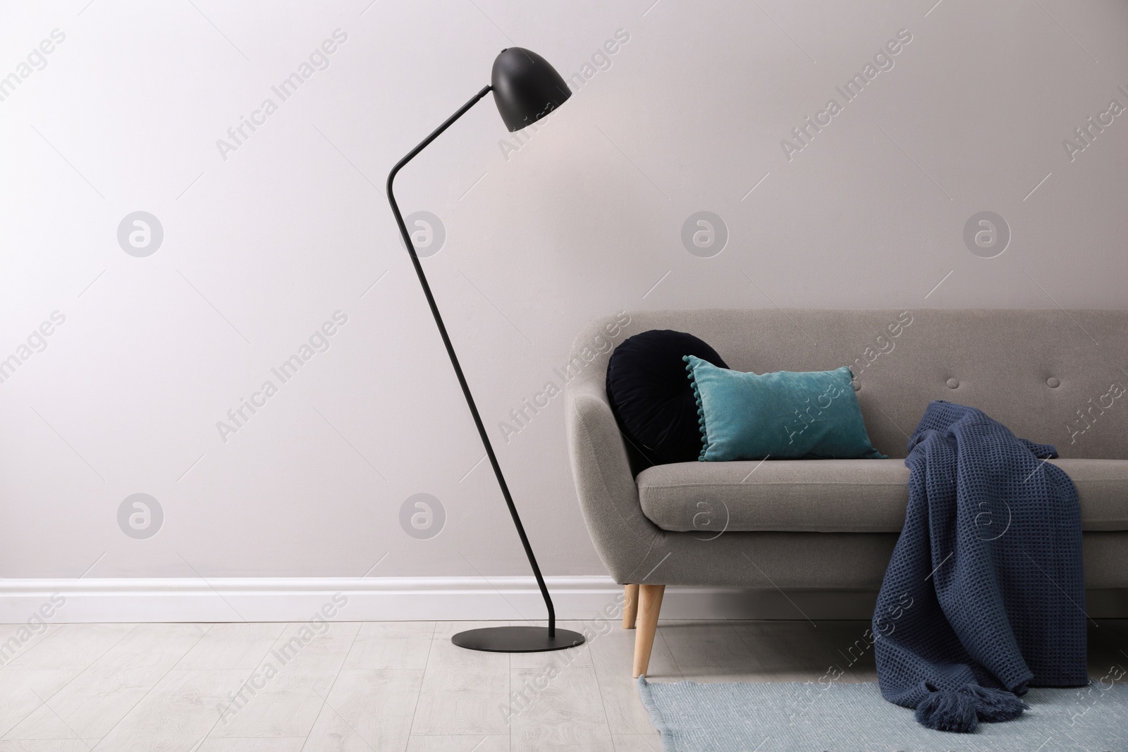 Photo of Stylish room living interior with comfortable sofa and lamp near white wall