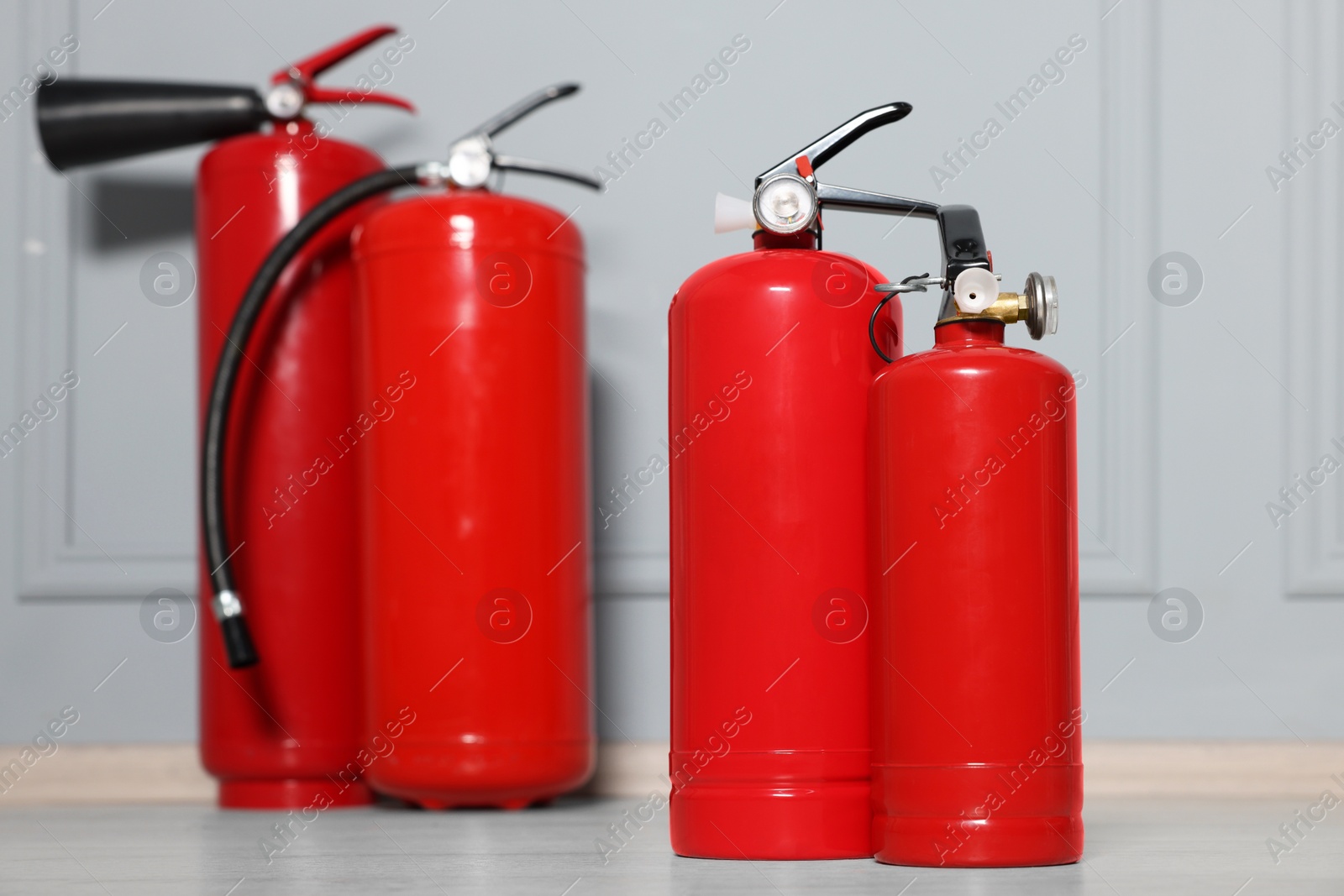 Photo of Red fire extinguishers near grey wall, selective focus