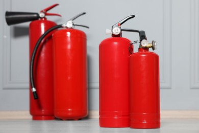 Red fire extinguishers near grey wall, selective focus