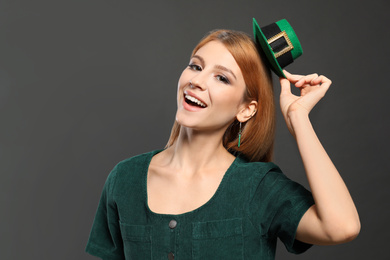 Photo of Young woman with green leprechaun hat on grey background. St. Patrick's Day celebration