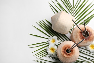 Photo of Fresh coconuts with drinking straws and flowers on white background, flat lay. Space for text