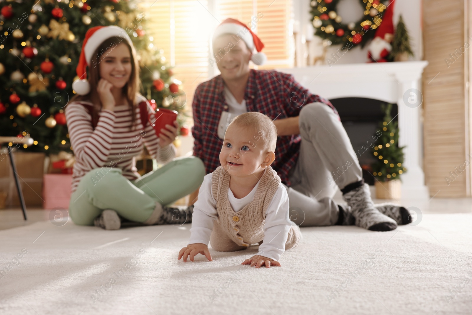 Photo of Happy family in room decorated for Christmas, focus on baby