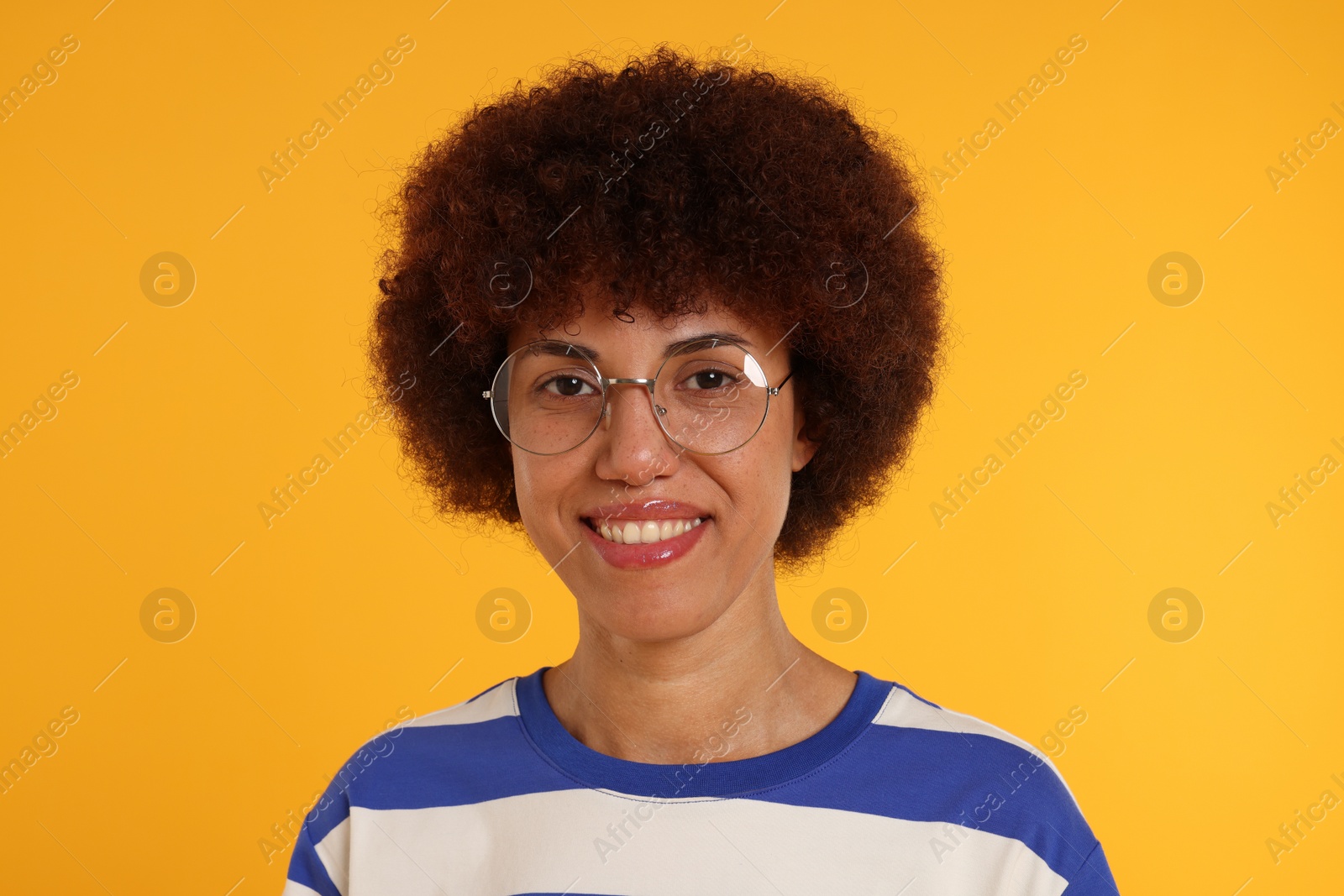 Photo of Portrait of happy young woman in eyeglasses on orange background