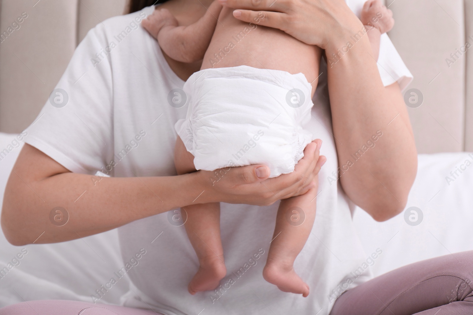 Photo of Mom holding her baby in diaper at home, closeup