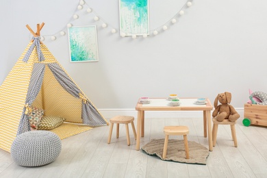 Photo of Cozy kids room interior with table, play tent and toys