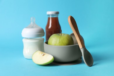 Photo of Healthy baby food, milk, apples and spoon on light blue background