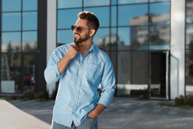 Photo of Handsome smiling man in sunglasses on city street, space for text