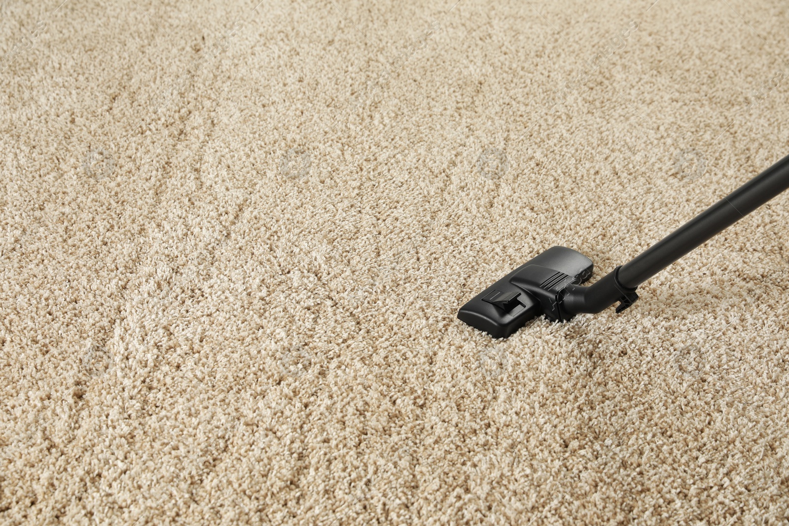 Photo of Removing dirt from beige carpet with modern vacuum cleaner. Space for text