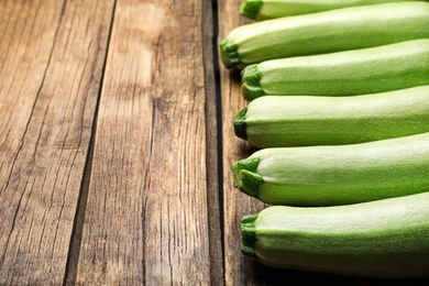 Photo of Raw green zucchinis on wooden table. Space for text