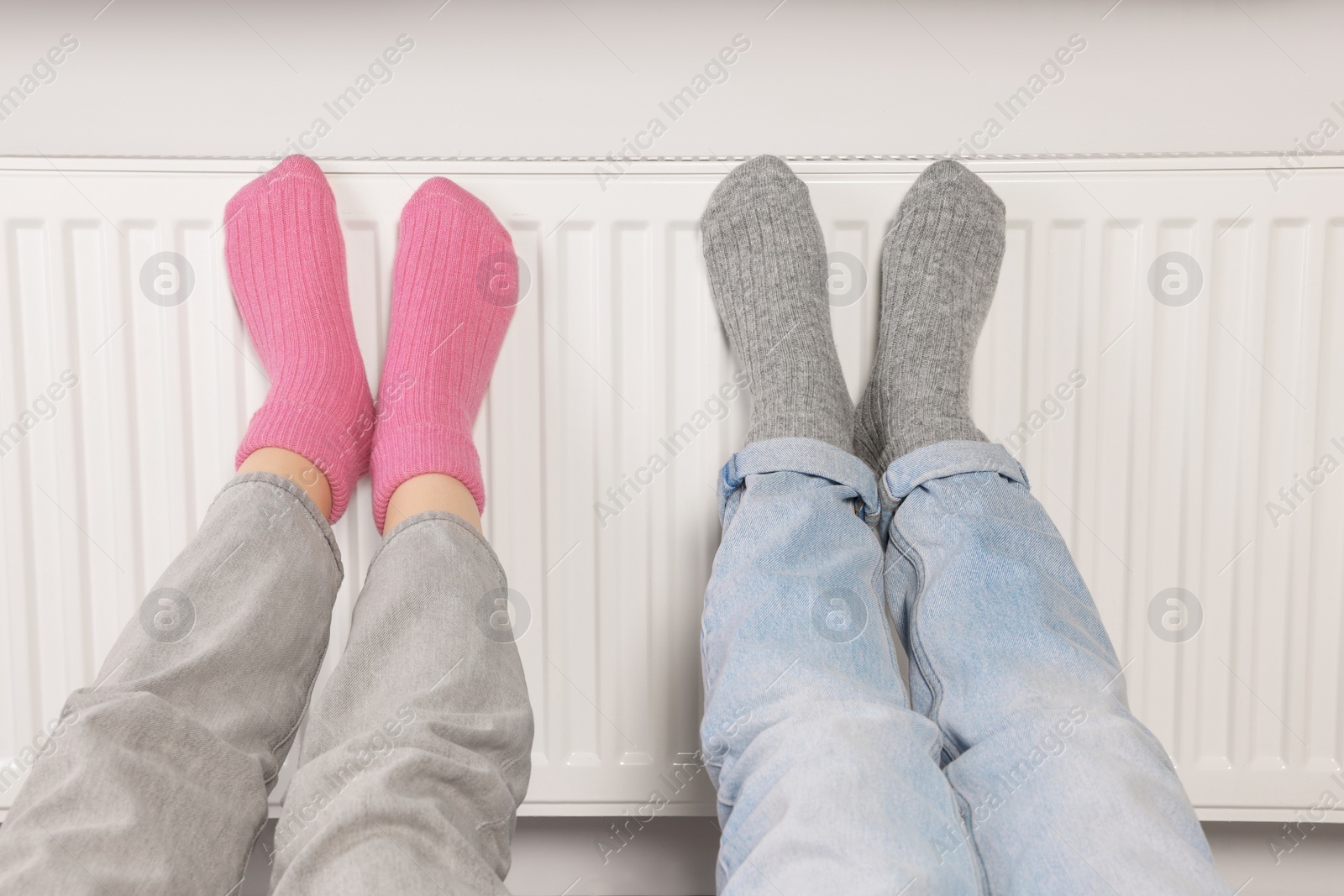 Photo of People warming feet near heating radiator, closeup