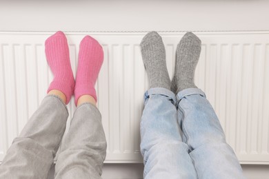 Photo of People warming feet near heating radiator, closeup