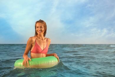 Beautiful woman with inflatable ring in sea, space for text