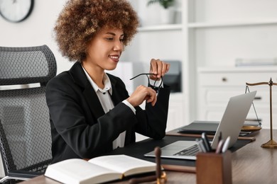 Photo of Notary with glasses using laptop at workplace in office