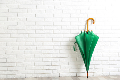Photo of Beautiful green umbrella near white brick wall. Space for text