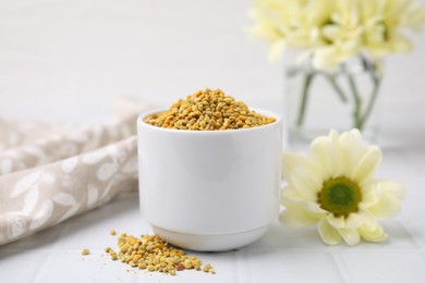 Fresh bee pollen granules and flower on white table