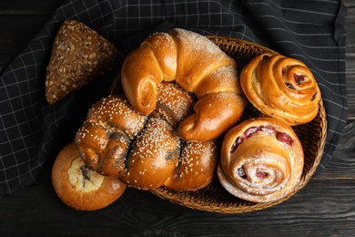 Photo of Different delicious fresh pastries on dark wooden background, flat lay