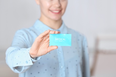 Photo of Woman holding business card indoors, closeup. Medical service