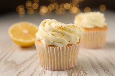 Photo of Tasty cupcakes with cream and lemon zest on white wooden table, closeup