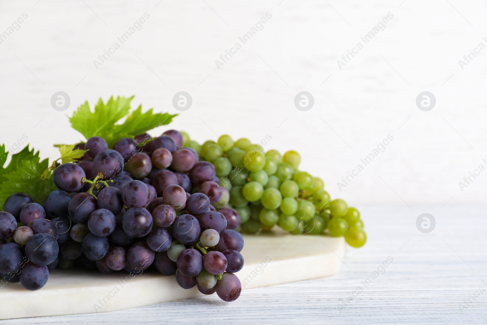 Photo of Fresh ripe juicy grapes on white wooden table