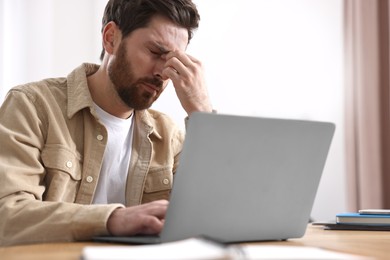 Tired man suffering from headache at workplace in office