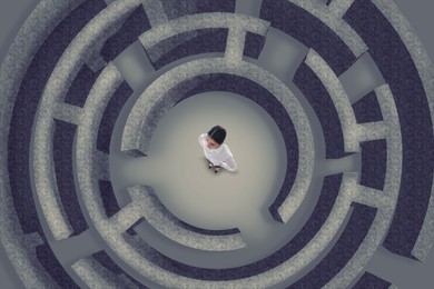 Businesswoman trying to find way out of maze, above view