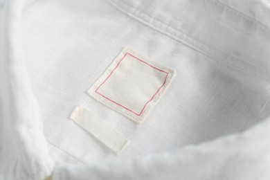 Photo of Blank clothing labels on white shirt, closeup