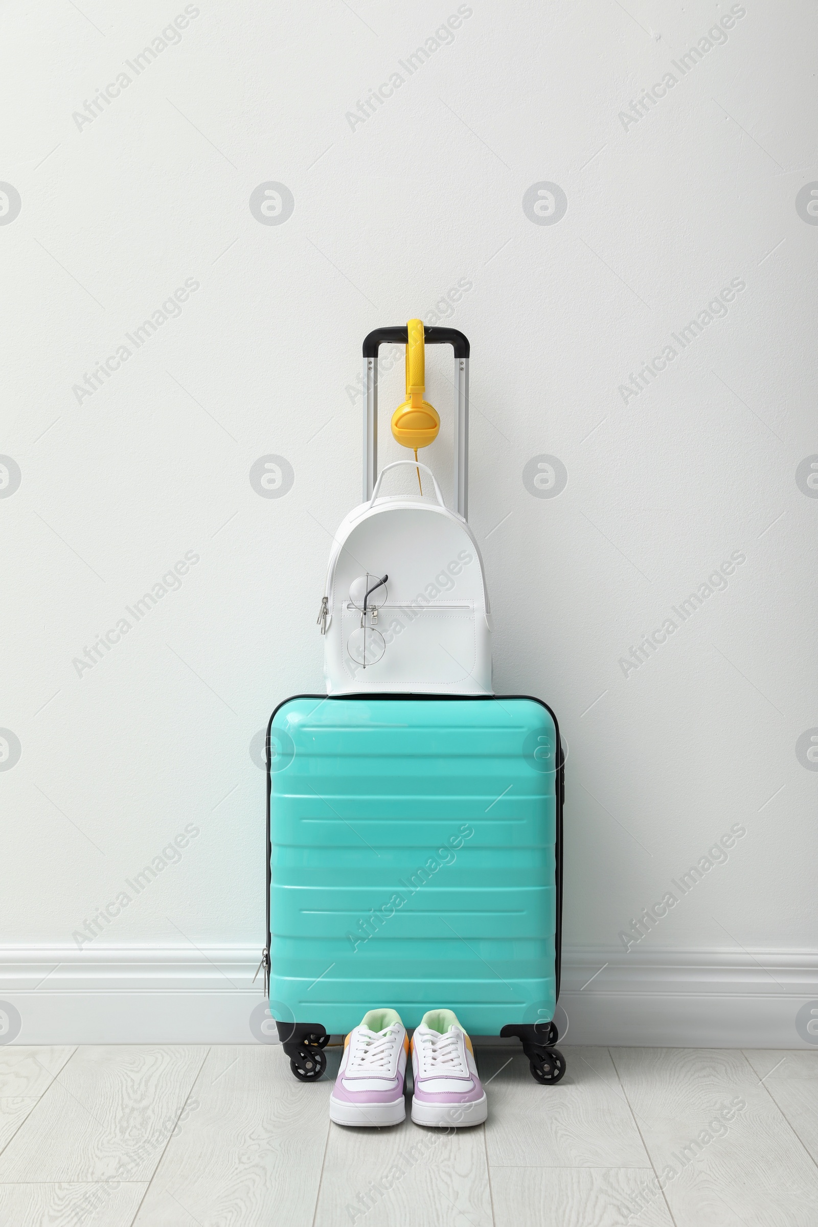 Photo of Suitcase packed for trip, shoes and accessories near white wall indoors