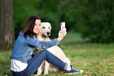 Photo of Young woman taking selfie together with her dog in park. Pet care