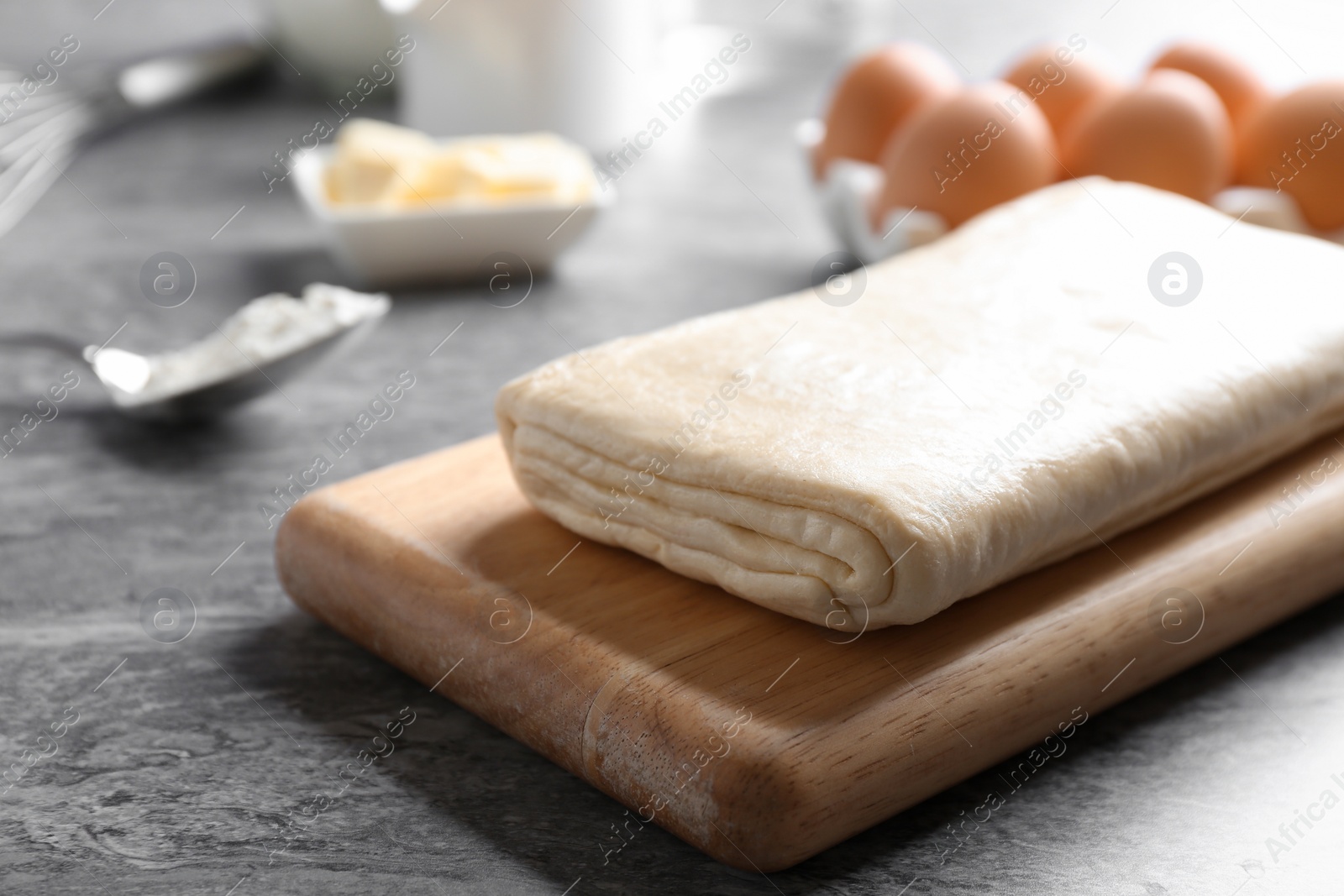 Photo of Board with puff pastry dough on grey table