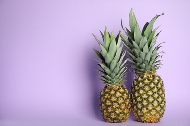 Photo of Fresh ripe juicy pineapples on lilac background. Space for text