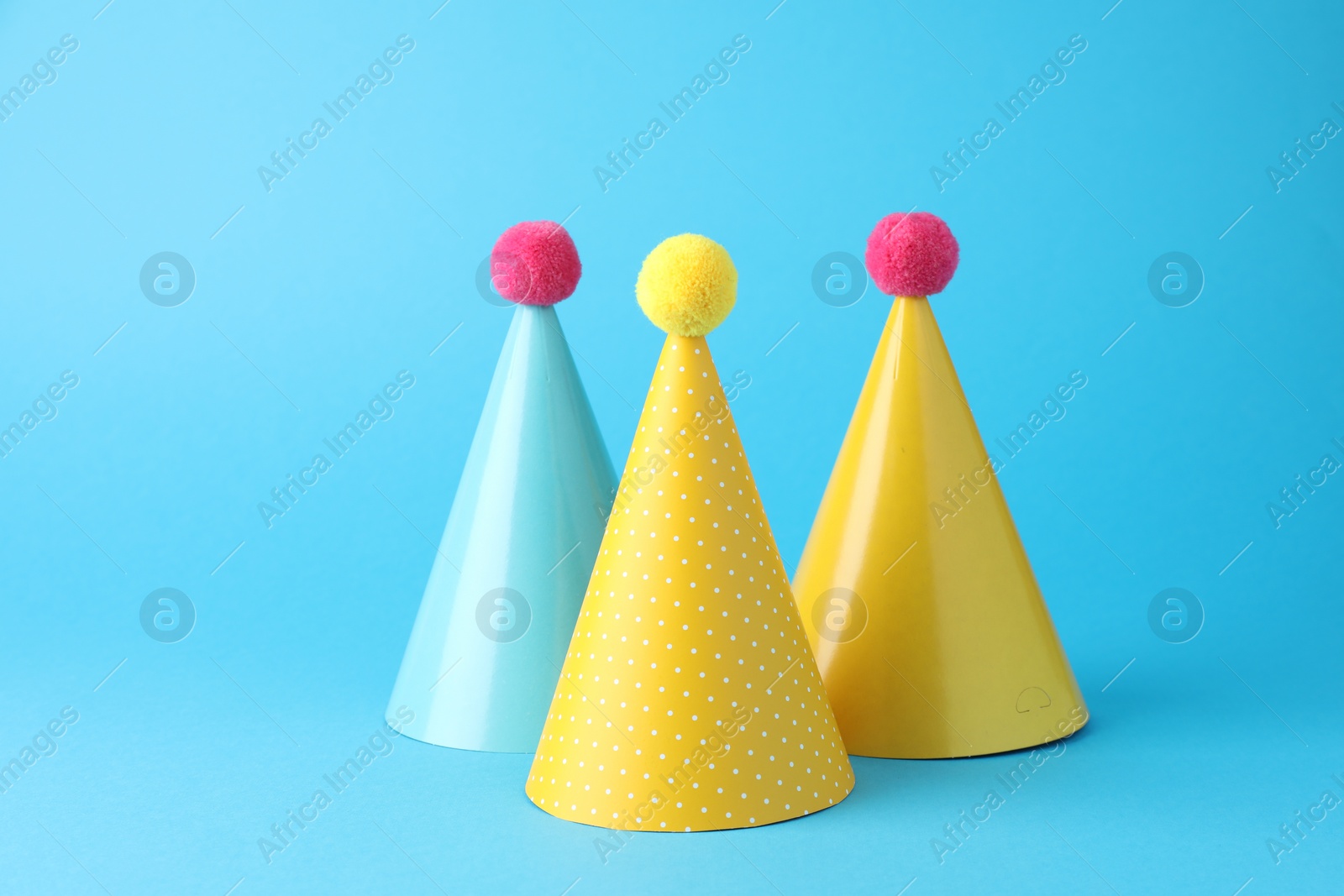 Photo of Colorful party hats on light blue background