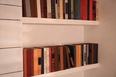 Photo of Collection of different books on shelves. Home library