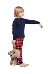 Photo of Boy in pajamas with toy bear sleepwalking on white background